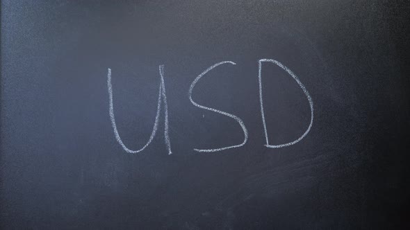 USD written on chalkboard. World currency. Hand writing USD with chalk on blackboard.