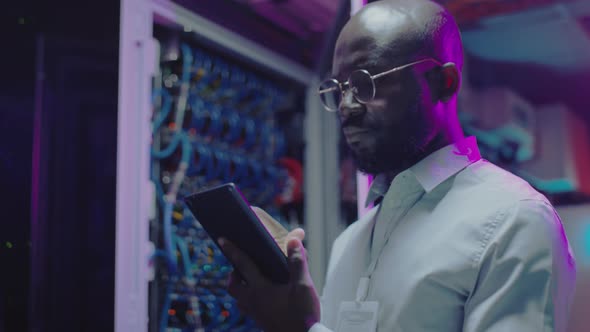 African American IT Engineer Working on Tablet in Data Center