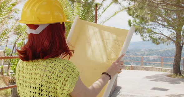 Female engineer looking at the project in the mountains with a yellow helmet