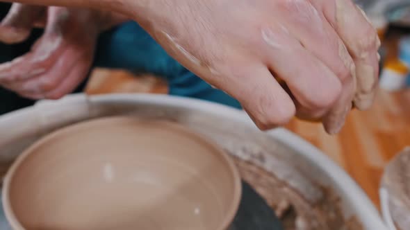 Man Potter Working with a Pot Using a Sponge - Removes Leftovers of the Clay