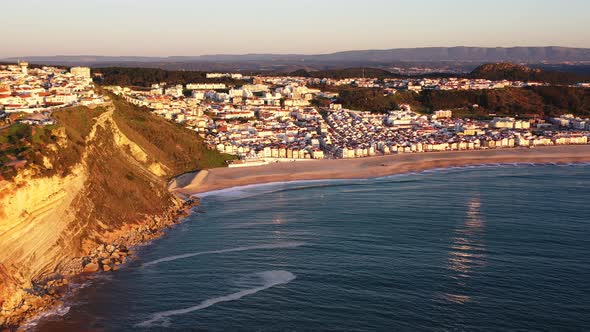 Town of Nazare Portugal during sunset golden hour, Aerial pan right reveal