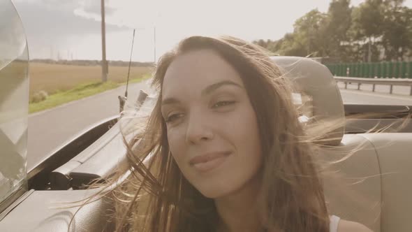 Young beautiful and smiling hipster girl in convertible car