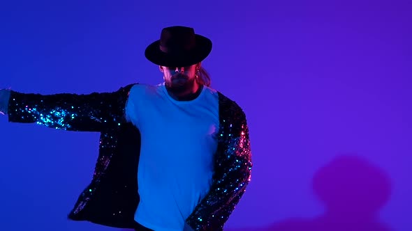 Young Stylish Man Dancing in Style Michael Jackson, Spotlight on a Blue Background