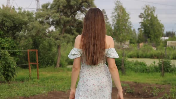 Woman Walking in Garden with Green Plants