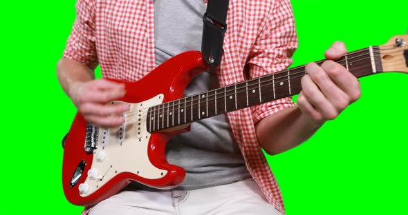 Mid section of male musician playing guitar