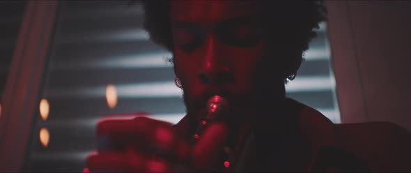 Close up of male musician playing the trumpet in a room with neon lights