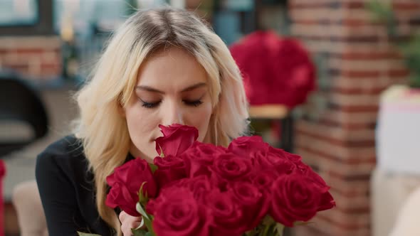 Portrait of Seductive Woman in Love Smelling Red Rose and Looking at Camera Enjoying Valentine Day