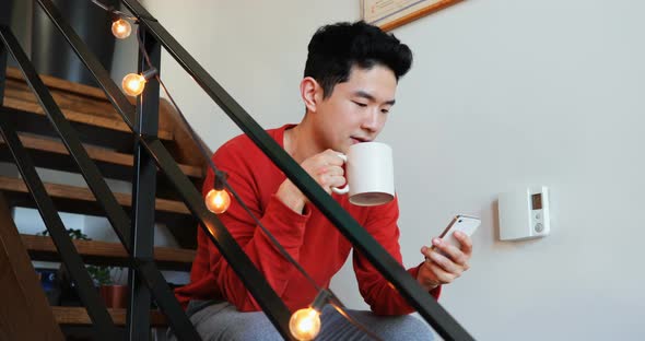 Man having coffee while using mobile phone on stair 4