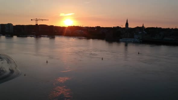 Golden sunset over silhouette of city with church tower and crane, aerial view