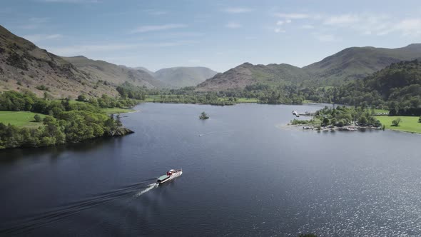 A steamer boat on Ullswater lake in the English Lake District sails towards Glenridding on a bright