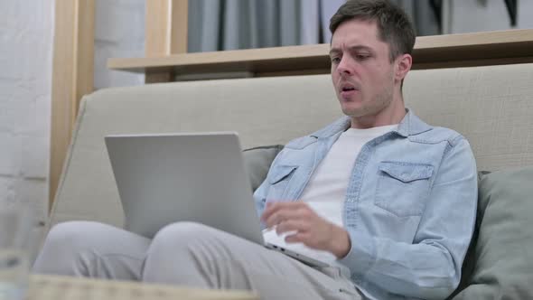 Young Man Upset By Loss on Laptop in Living Room