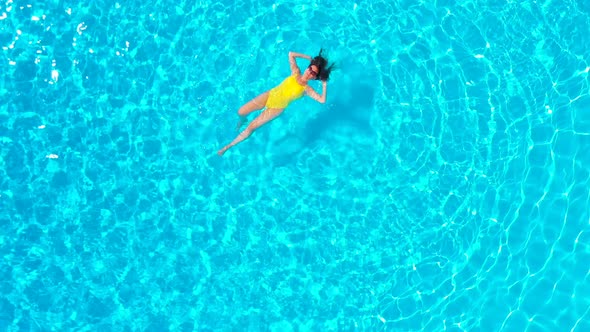 View From the Top As a Woman in a Yellow Swimsuit Lying on Her Back in the Pool