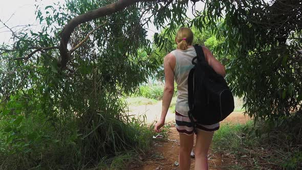 girl tourist with a backpack out of the forest on a tropical island. seascape