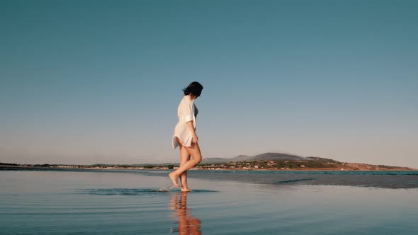 A woman walks barefoot on the beach