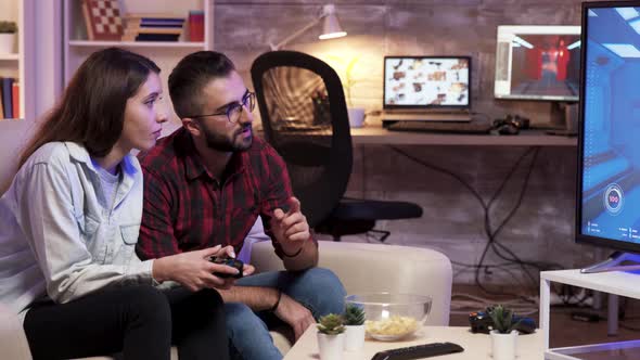 Man Sitting on Couch Learning His Girlfriend To Play Video Games