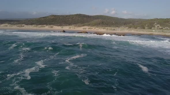 Green ocean waves break onto Buffalo Bay beach, South Africa, aerial