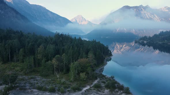 Plansee, Tyrol, Austrian Alps - 4K 60fps Aerial - Flying Above the Forest and Water on a Foggy Day