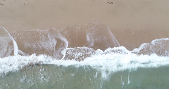 Static top down view of tropical beach, foamy ocean waves washing sand, Waves hitting sand beach