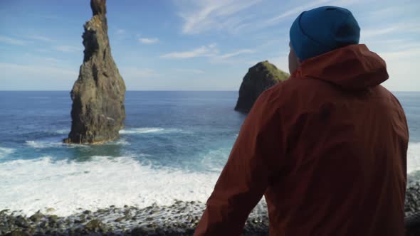 Young man admiring ocean and rocky coast view