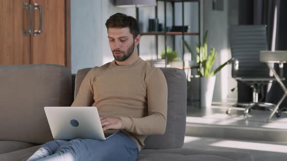 Young man experiencing stress at work with laptop at home