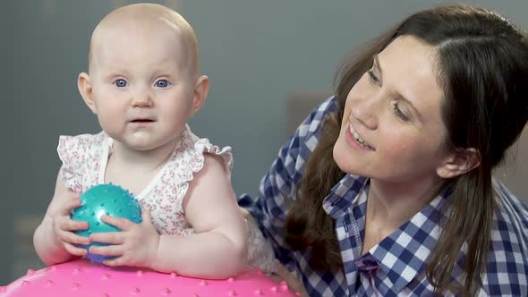 Woman Holding Small Child on Fitness Ball, Dandling Up and Down, Playful Baby