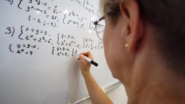 Elderly Teacher is Writing Equation on the Whiteboard