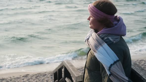 Woman in Warm Clothes Breathes Fresh Air on the Beach in Winter