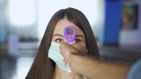 Woman in mask is checked for temperature in a mall