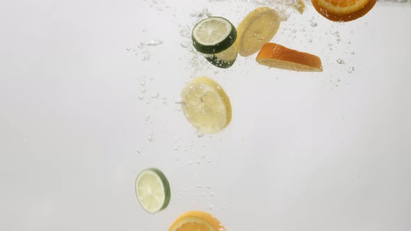 Orange, Lemon and Lime Slices Falling Into Water with Bubbles on White Background. Сitrus Falling