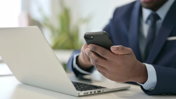 African Businessman with Laptop Using Smartphone Close Up