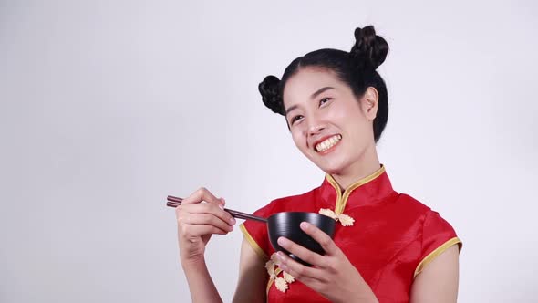 happy woman wearing chinese cheongsam dress with chopsticks and bowl