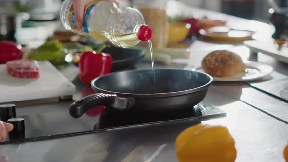 Gourmet Chef Pouring Sunflower Oil From Bottle in Frying Pan