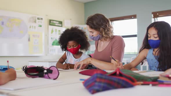 Female teacher wearing face mask teaching a girl in class