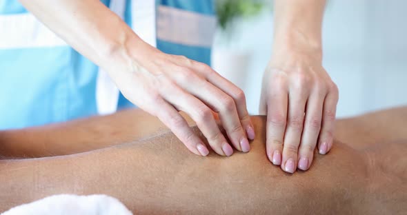 Hands of Professional Massage Therapist Make Wellness Massage of Legs and Feet for Client