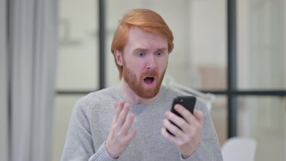 Portrait of Young Redhead Man Loss on Smartphone