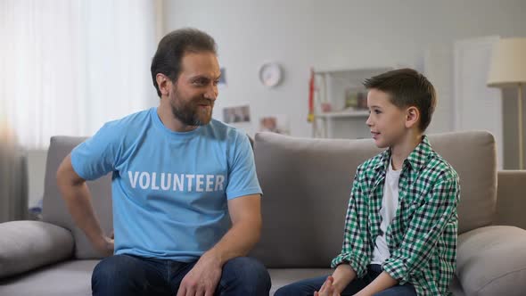 Attentive Smiling Volunteer Giving Orphan Boy Soccer Ball, Dreams Come True