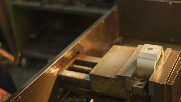 Caucasian male hands factory worker at a factory standing at a workbench and using a hummer