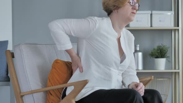 Working Old Senior Woman with Back Pain Sitting on Couch