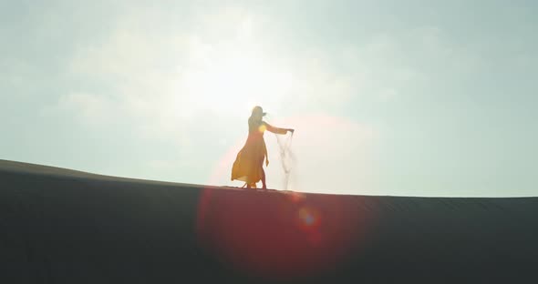 Silhouette of Woman Dispelling Sand in Air From Hands