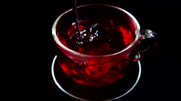 Preparation of Hibiscus tea in a glass cup.