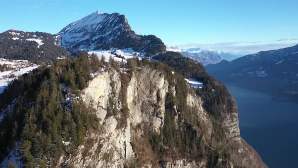 Aerial forward shot of snow covered observation platform on top of mountain against blue sky. Lake i