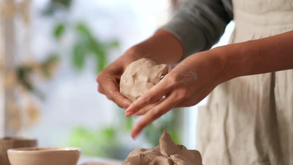 Female hands sculpt a bowl of clay