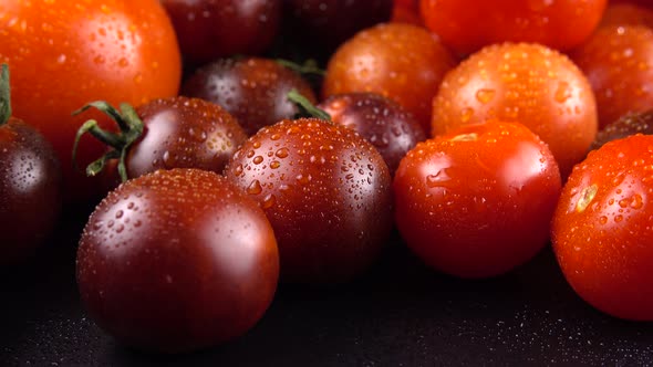 Cherry tomatoes on a black background in water drops.