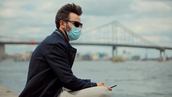 Man Sitting In Protective Mask COVID19 Virus Disease. Businessman In Face Mask On Quarantine.