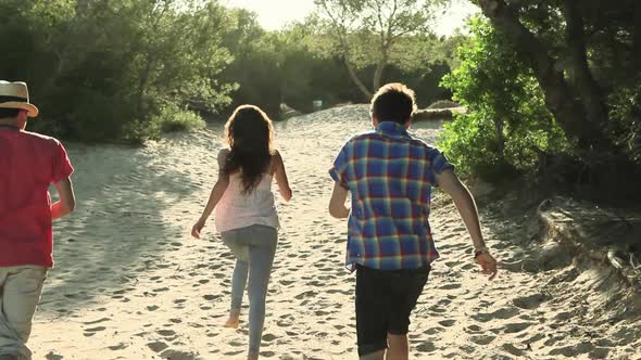 Three young friends running on sand