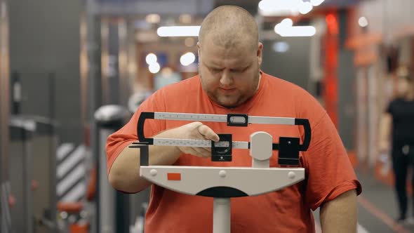 Attractive and Overweight Man Standing on a Mechanical Scale