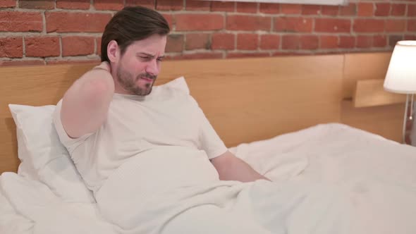 Casual Young Man Having Neck Pain in Bed