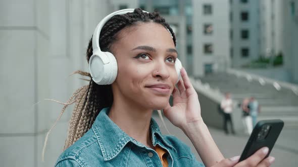 Mixed Race Woman Listening Music on the Street and Holding Smartphone