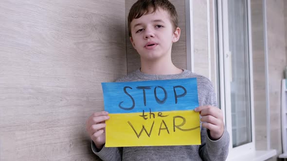 Child Holds in Hands a Poster with a Flag of Ukraine and Message Stop the War