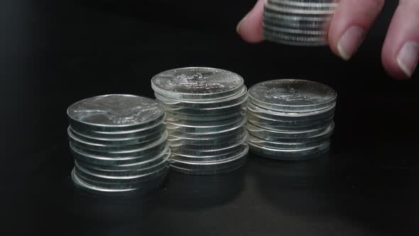 Silver coins (American Silver Eagles) being stacked by hand